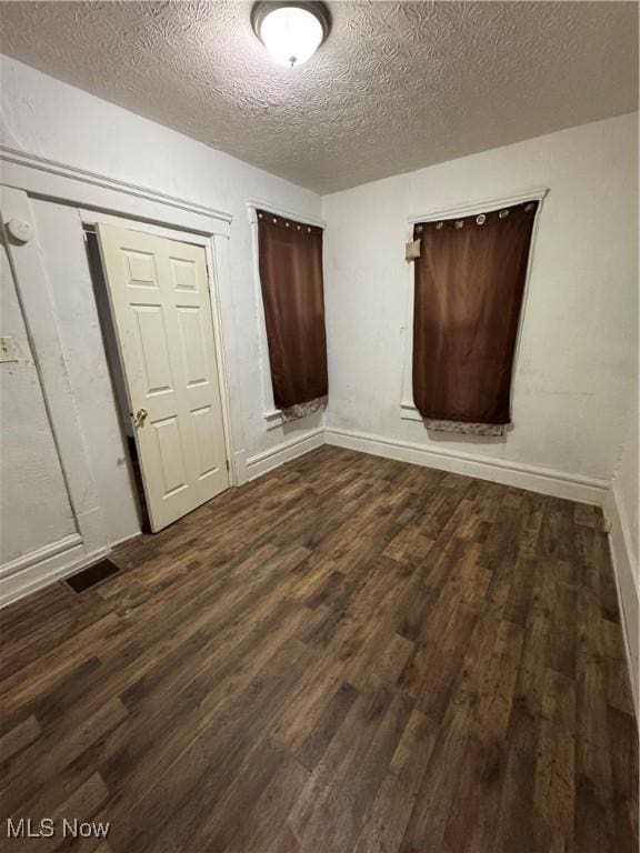 unfurnished bedroom with dark wood-type flooring, a closet, and a textured ceiling