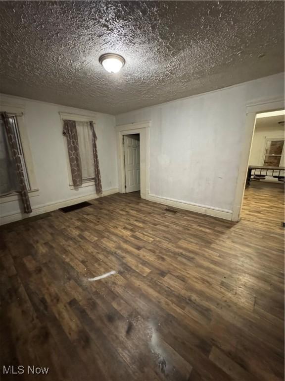 unfurnished room with wood-type flooring and a textured ceiling