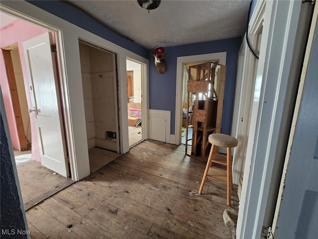 corridor with hardwood / wood-style floors and a textured ceiling