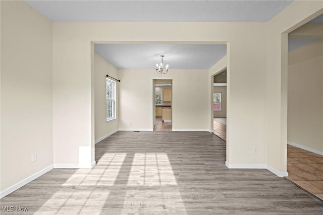 spare room featuring an inviting chandelier and hardwood / wood-style flooring