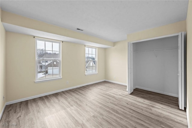 unfurnished bedroom with a closet and light wood-type flooring