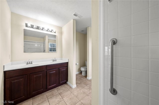 bathroom with tile patterned flooring, vanity, a textured ceiling, a shower, and toilet