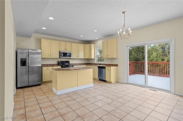 kitchen featuring decorative light fixtures, a center island, appliances with stainless steel finishes, a notable chandelier, and cream cabinets