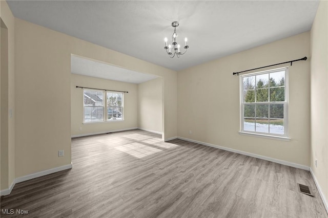 spare room featuring a notable chandelier and light hardwood / wood-style flooring