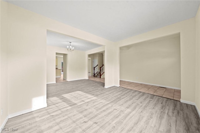 unfurnished room featuring an inviting chandelier and light hardwood / wood-style floors