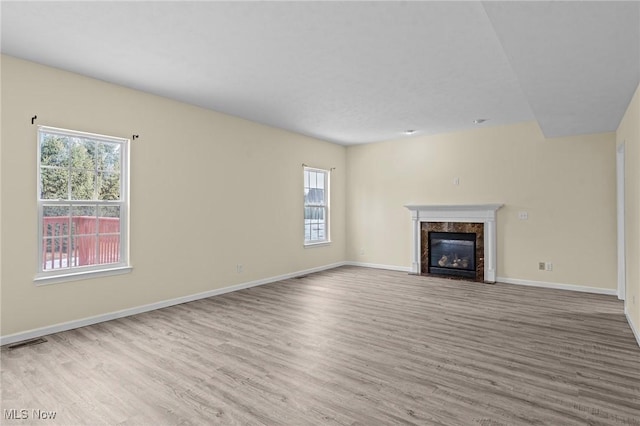 unfurnished living room featuring a premium fireplace and light hardwood / wood-style flooring