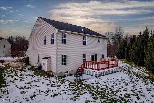 snow covered house featuring a wooden deck and cooling unit