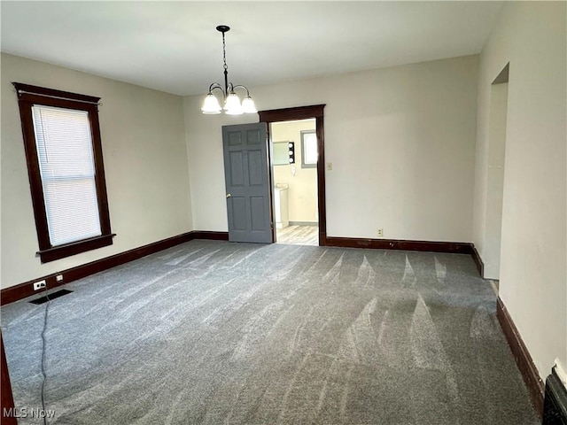 empty room featuring a chandelier and dark colored carpet