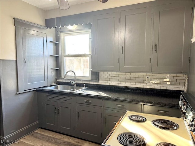 kitchen featuring sink, gray cabinets, electric stove, light hardwood / wood-style floors, and backsplash