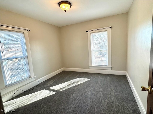 spare room featuring dark carpet