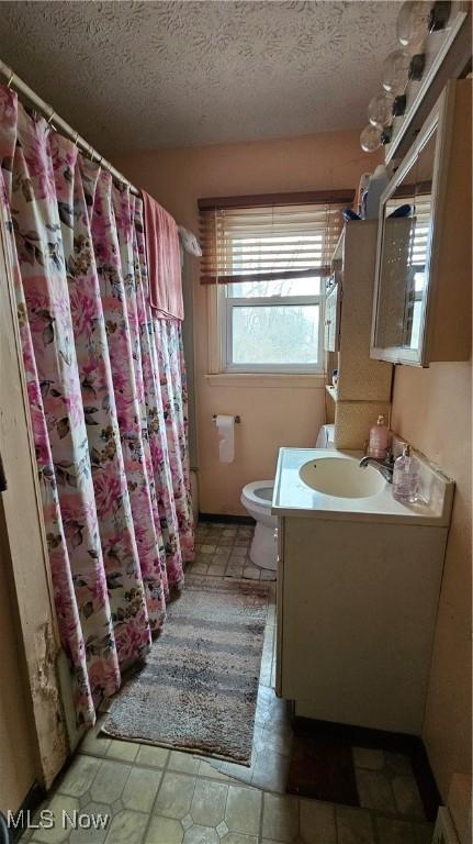 bathroom featuring vanity, toilet, and a textured ceiling