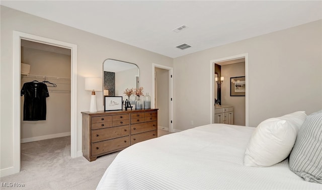 bedroom featuring light colored carpet, connected bathroom, a spacious closet, and a closet