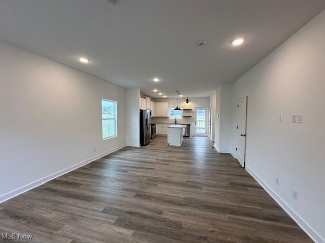 unfurnished living room with dark wood-style flooring, baseboards, and recessed lighting