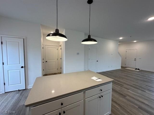 kitchen featuring baseboards, a center island, white cabinets, dark wood finished floors, and hanging light fixtures