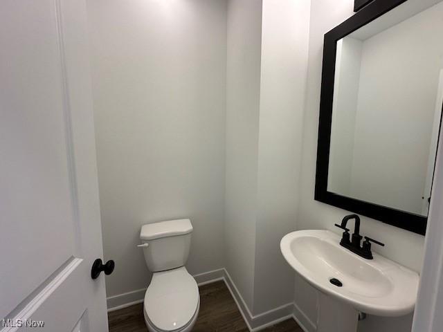 bathroom featuring toilet, wood finished floors, a sink, and baseboards
