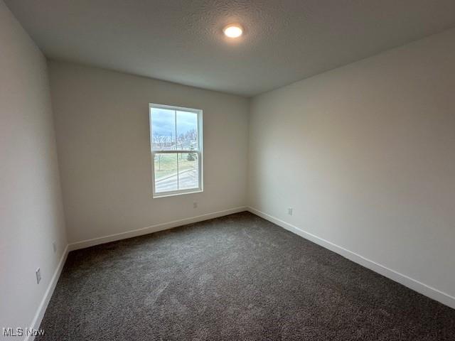 empty room featuring recessed lighting, baseboards, and dark carpet