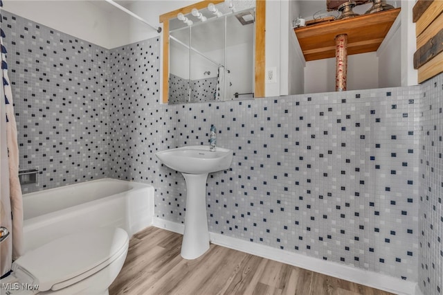 bathroom featuring washtub / shower combination, toilet, and hardwood / wood-style floors