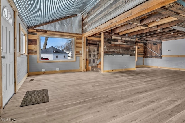 interior space with lofted ceiling, light hardwood / wood-style floors, and wood walls