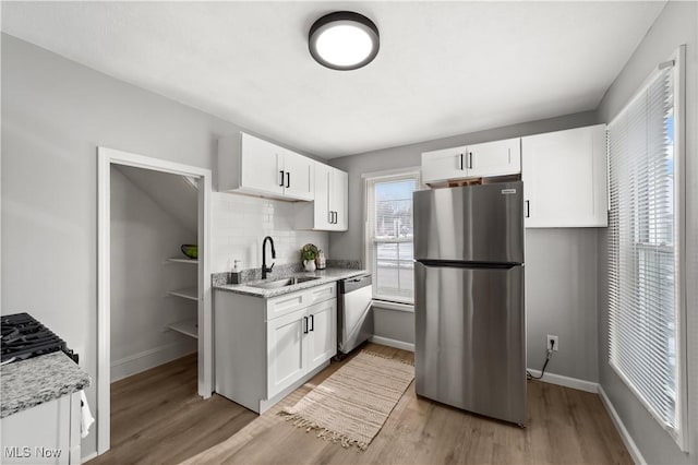 kitchen with appliances with stainless steel finishes, light stone countertops, sink, and white cabinets