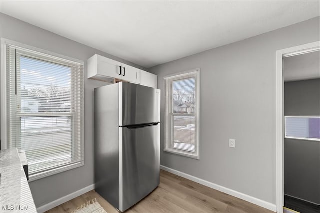 kitchen with white cabinets, stainless steel refrigerator, and light hardwood / wood-style floors