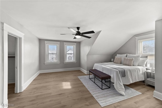 bedroom with ceiling fan, light hardwood / wood-style floors, and multiple windows