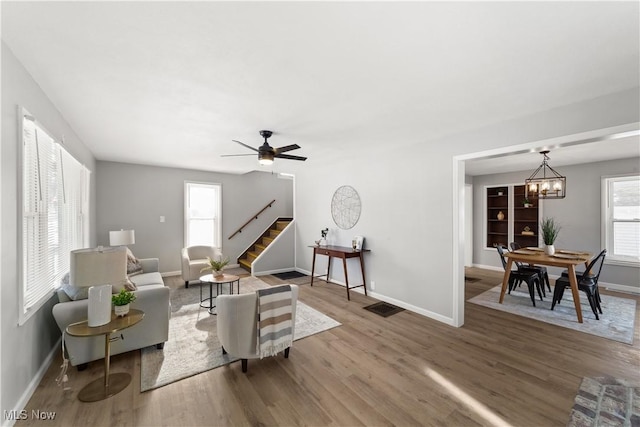 living room featuring ceiling fan with notable chandelier, plenty of natural light, and wood-type flooring