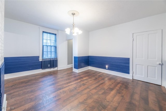 unfurnished room featuring a notable chandelier and dark wood-type flooring