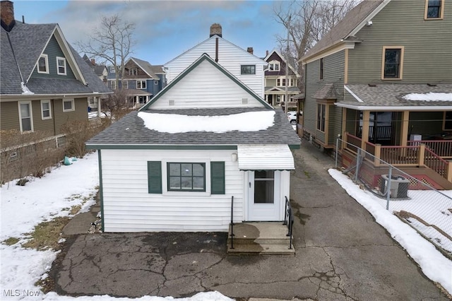 snow covered back of property featuring covered porch