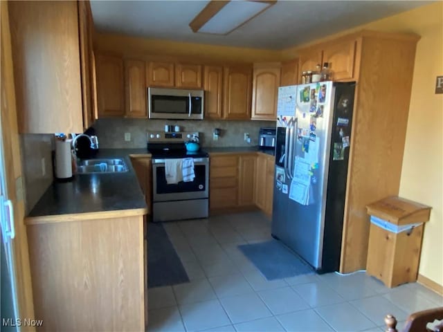 kitchen featuring tasteful backsplash, appliances with stainless steel finishes, light tile patterned flooring, and sink