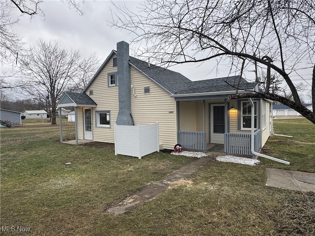 back of property with a yard and a porch