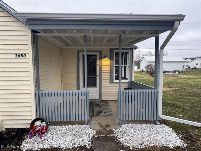 doorway to property with a yard and covered porch