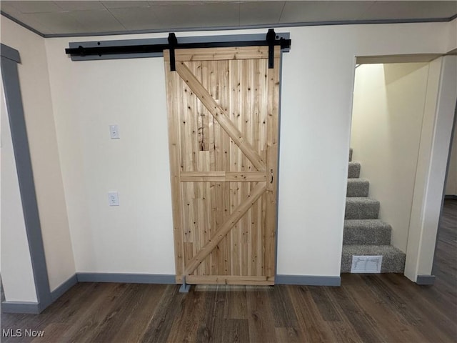 basement with a barn door and dark hardwood / wood-style floors