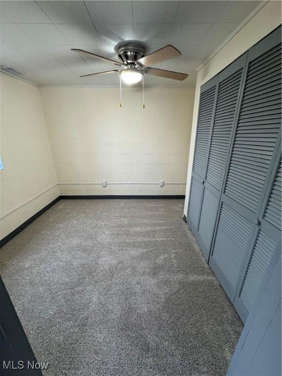 unfurnished bedroom featuring dark carpet, a closet, and ceiling fan