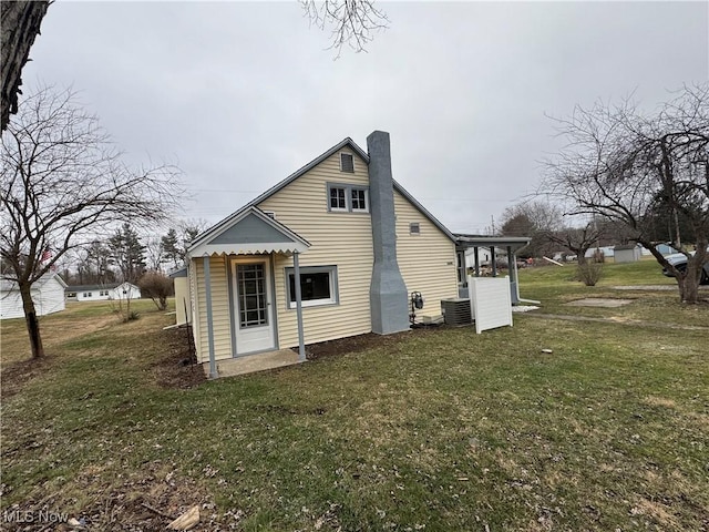 rear view of house with central AC and a lawn