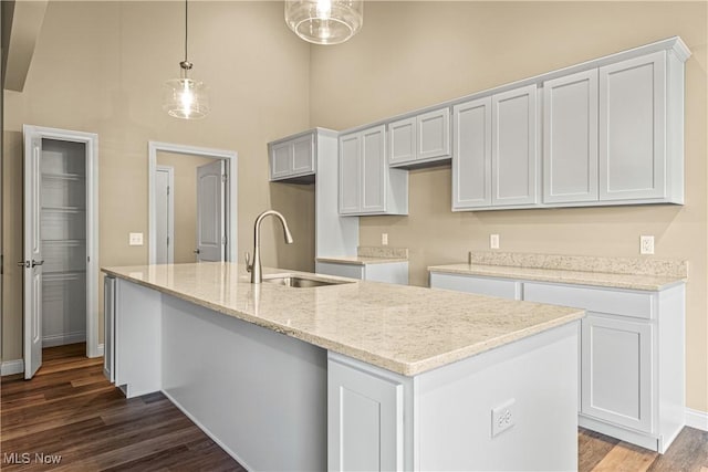 kitchen featuring pendant lighting, sink, an island with sink, and white cabinets