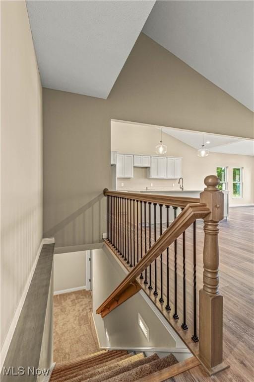 stairway featuring vaulted ceiling and hardwood / wood-style floors