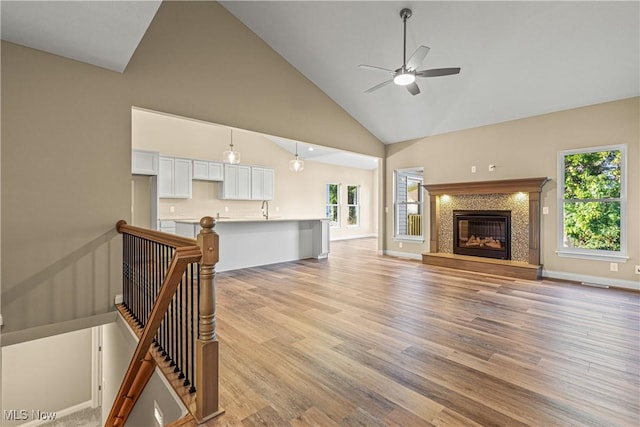 living room featuring high vaulted ceiling, light hardwood / wood-style floors, sink, and ceiling fan