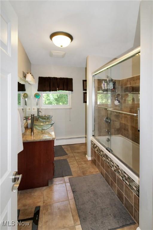 bathroom featuring vanity, tile patterned flooring, a baseboard radiator, and shower / bath combination with glass door