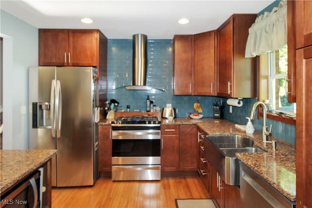 kitchen with sink, light stone countertops, wall chimney exhaust hood, and appliances with stainless steel finishes