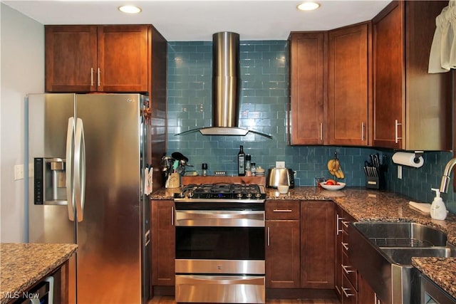 kitchen featuring wall chimney exhaust hood, stainless steel appliances, sink, and stone counters