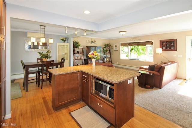 kitchen featuring crown molding, baseboard heating, a kitchen island, pendant lighting, and light stone countertops