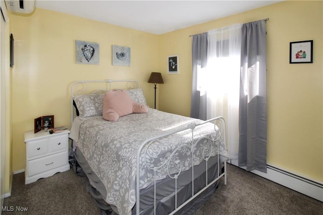 bedroom featuring an AC wall unit, baseboard heating, and dark colored carpet