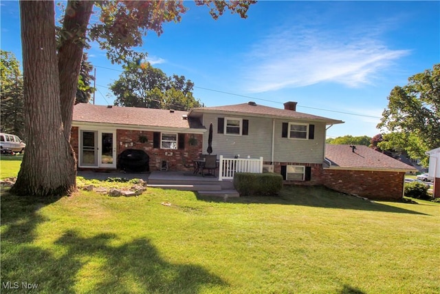 back of property with a wooden deck and a lawn