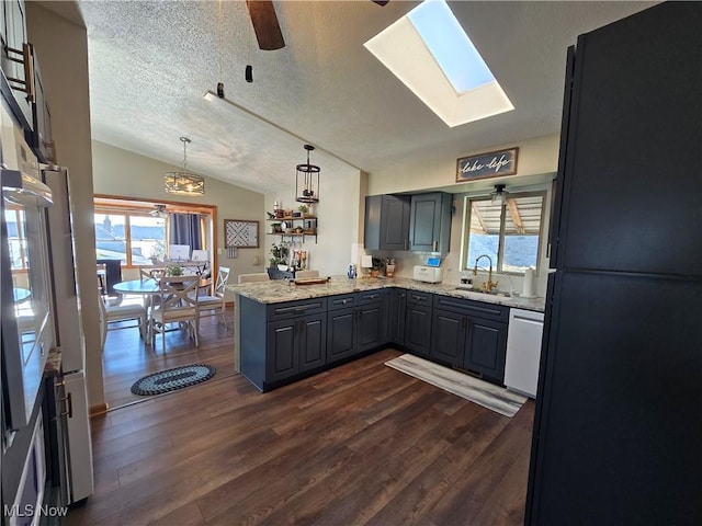 kitchen with lofted ceiling, gray cabinets, dishwasher, black fridge, and kitchen peninsula