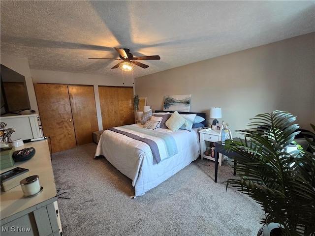 carpeted bedroom with multiple closets, ceiling fan, and a textured ceiling