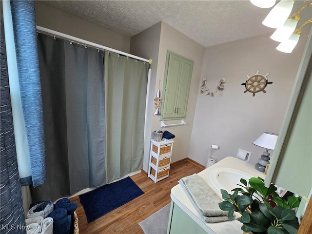 bathroom with wood-type flooring, vanity, and a textured ceiling