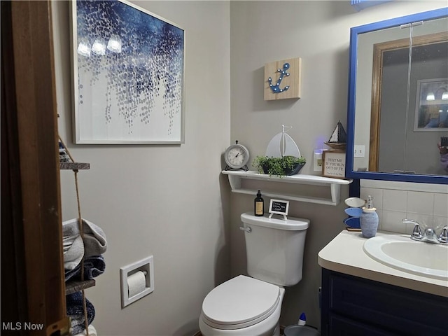 bathroom with vanity, toilet, and decorative backsplash