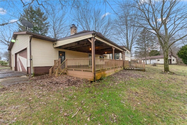 back of house featuring a garage, a wooden deck, and a yard