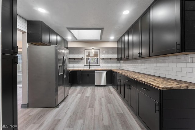 kitchen with sink, decorative backsplash, light wood-type flooring, and appliances with stainless steel finishes