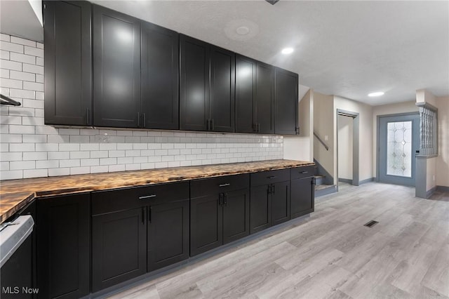 kitchen featuring wood counters, decorative backsplash, light hardwood / wood-style floors, and dishwasher